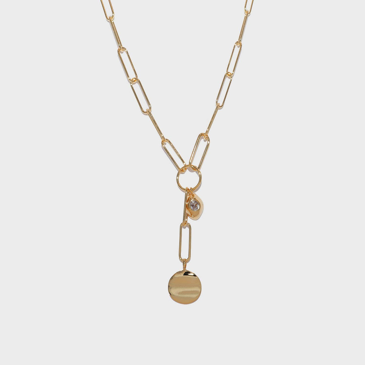 A gold paperclip chain necklace with a Y-shaped design, featuring a small bezel-set clear stone and a flat round disc pendant, shown on a light gray background.