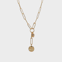 A gold paperclip chain necklace with a Y-shaped design, featuring a small bezel-set clear stone and a flat round disc pendant, shown on a light gray background.